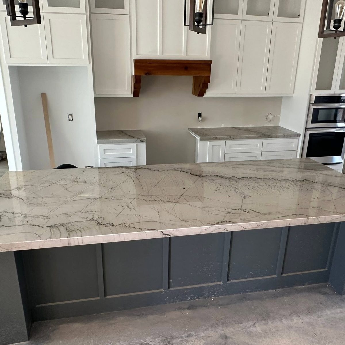 Large kitchen island with a veined stone top on a dark base.