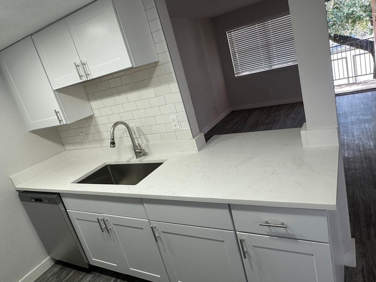 Kitchen counter with a light stone top, undermount sink, and subway tile backsplash.