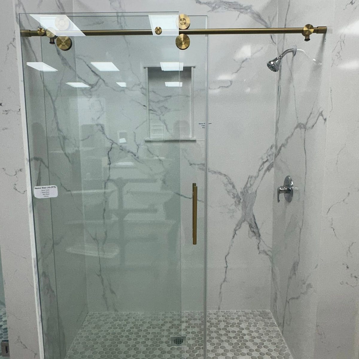 Shower with full-height veined stone wall panels and a glass door.