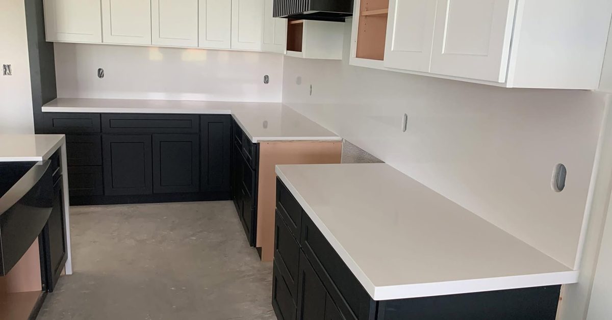 Kitchen with white quartz counters over black base cabinets and white uppers.
