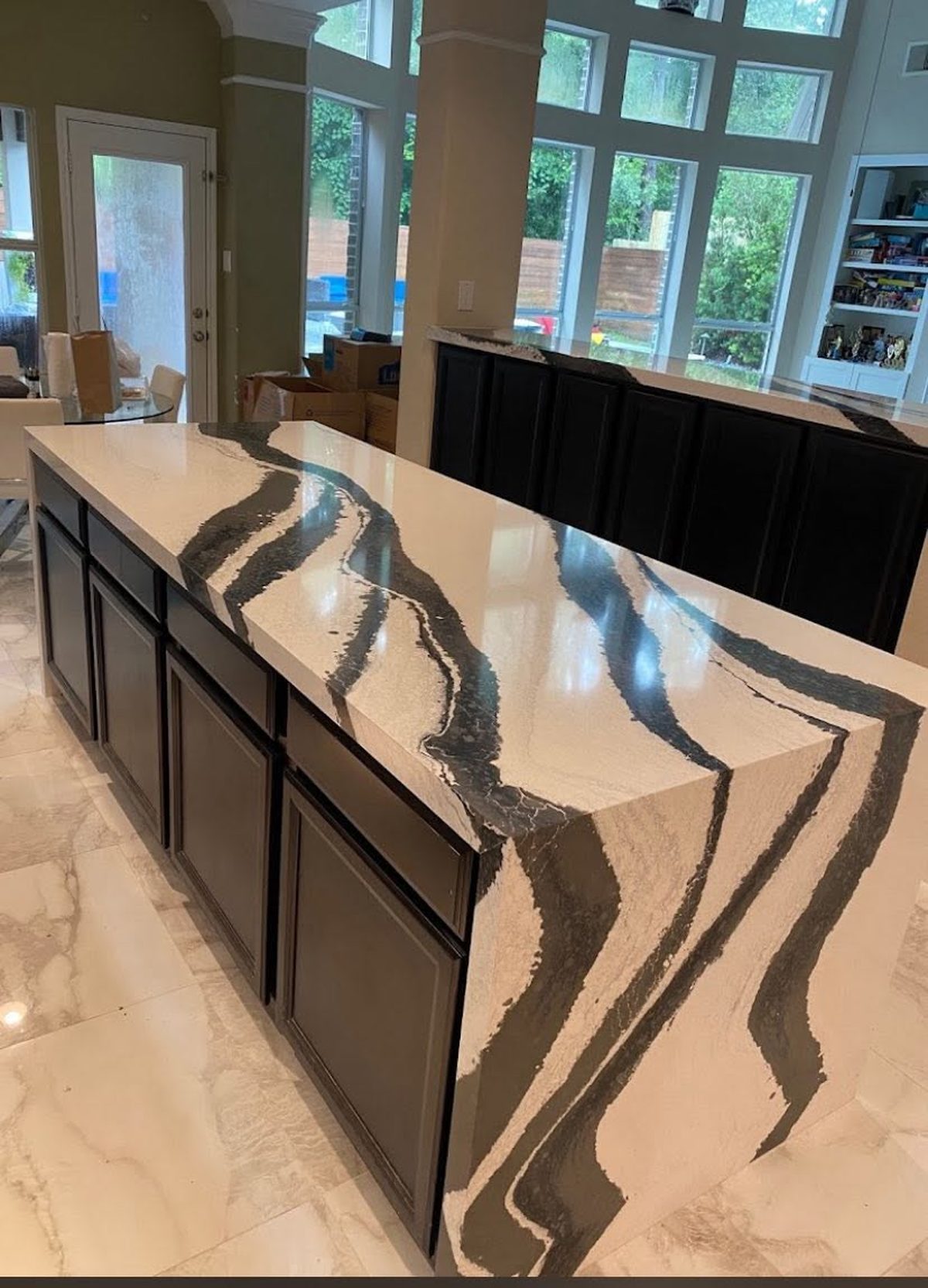 Kitchen island with bold black and white veined stone and a waterfall edge.