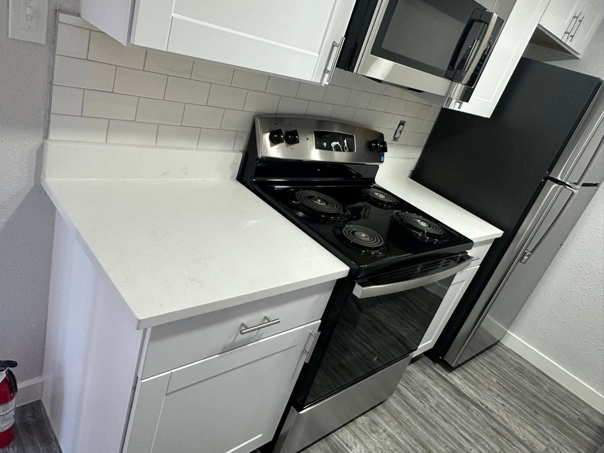 Kitchen corner with white stone counters, subway tile backsplash, and a range.