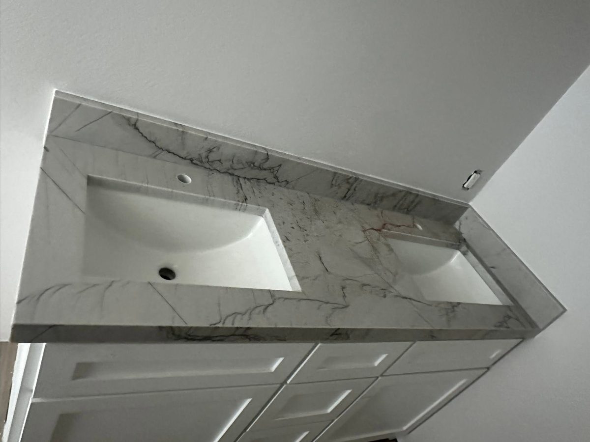Bathroom vanity top in white veined stone with two undermount sinks.