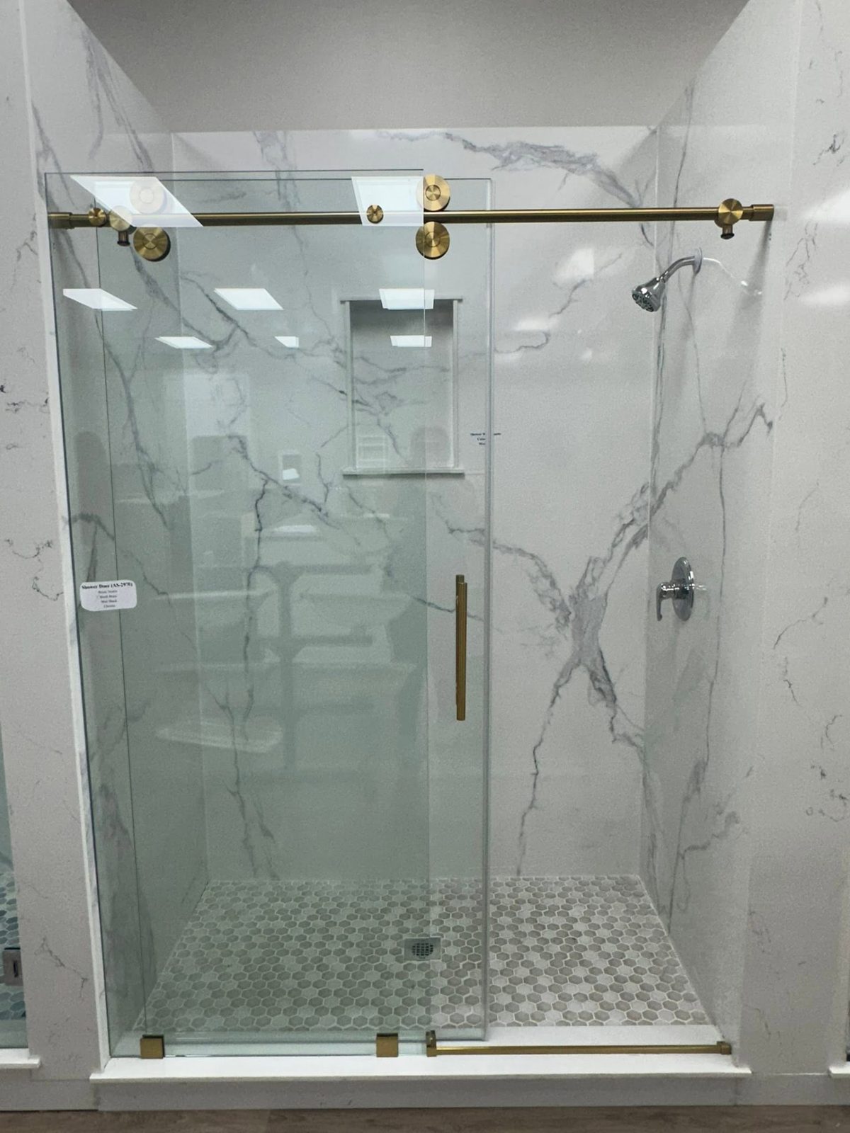 Shower with full-height white marble-look panels and a glass door with brass hardware.