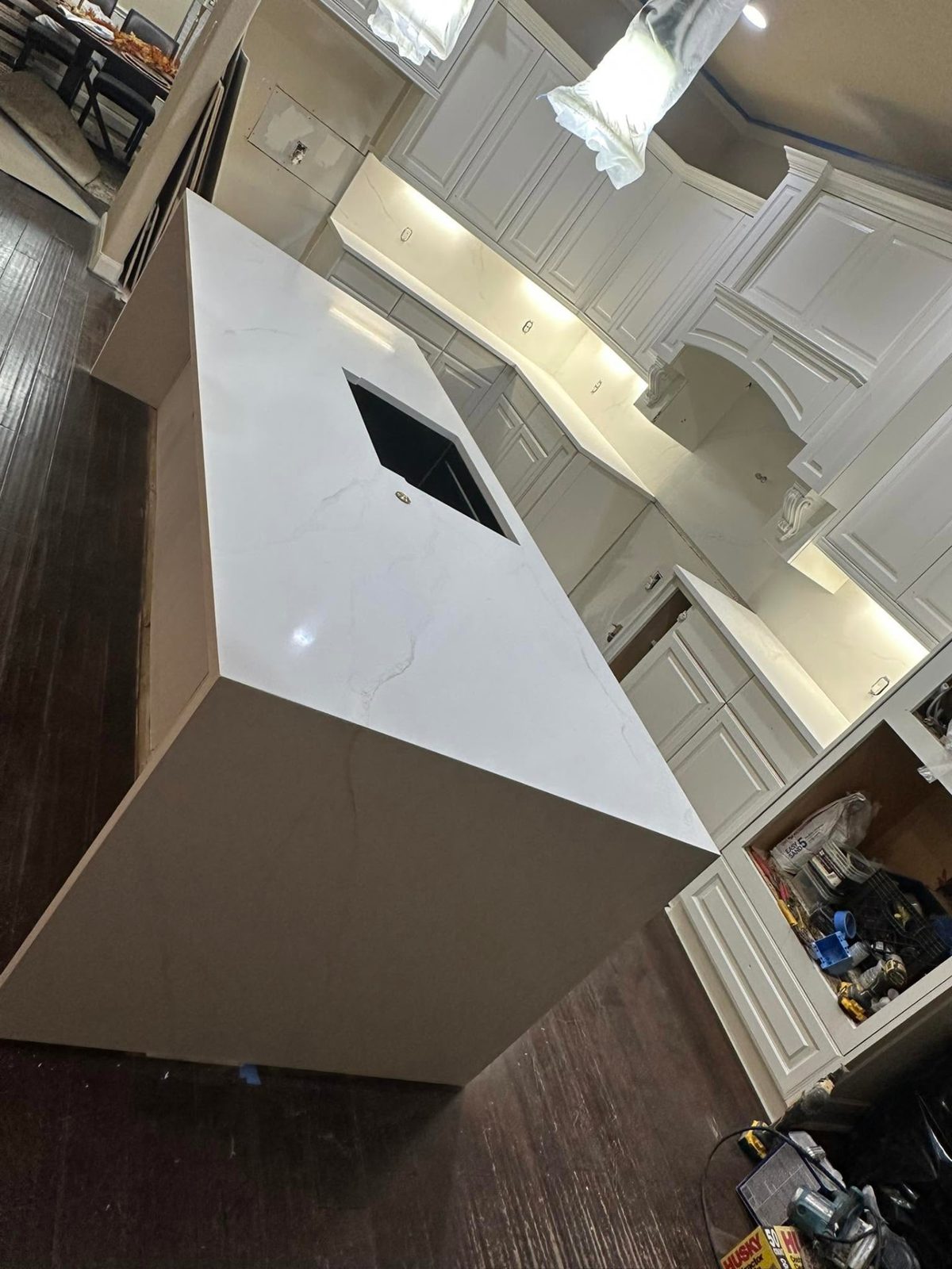 Kitchen island with a white veined stone top and mitered waterfall edge.
