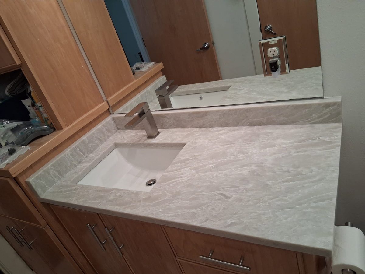Bathroom vanity in cream marbled stone with a backsplash and undermount sink.