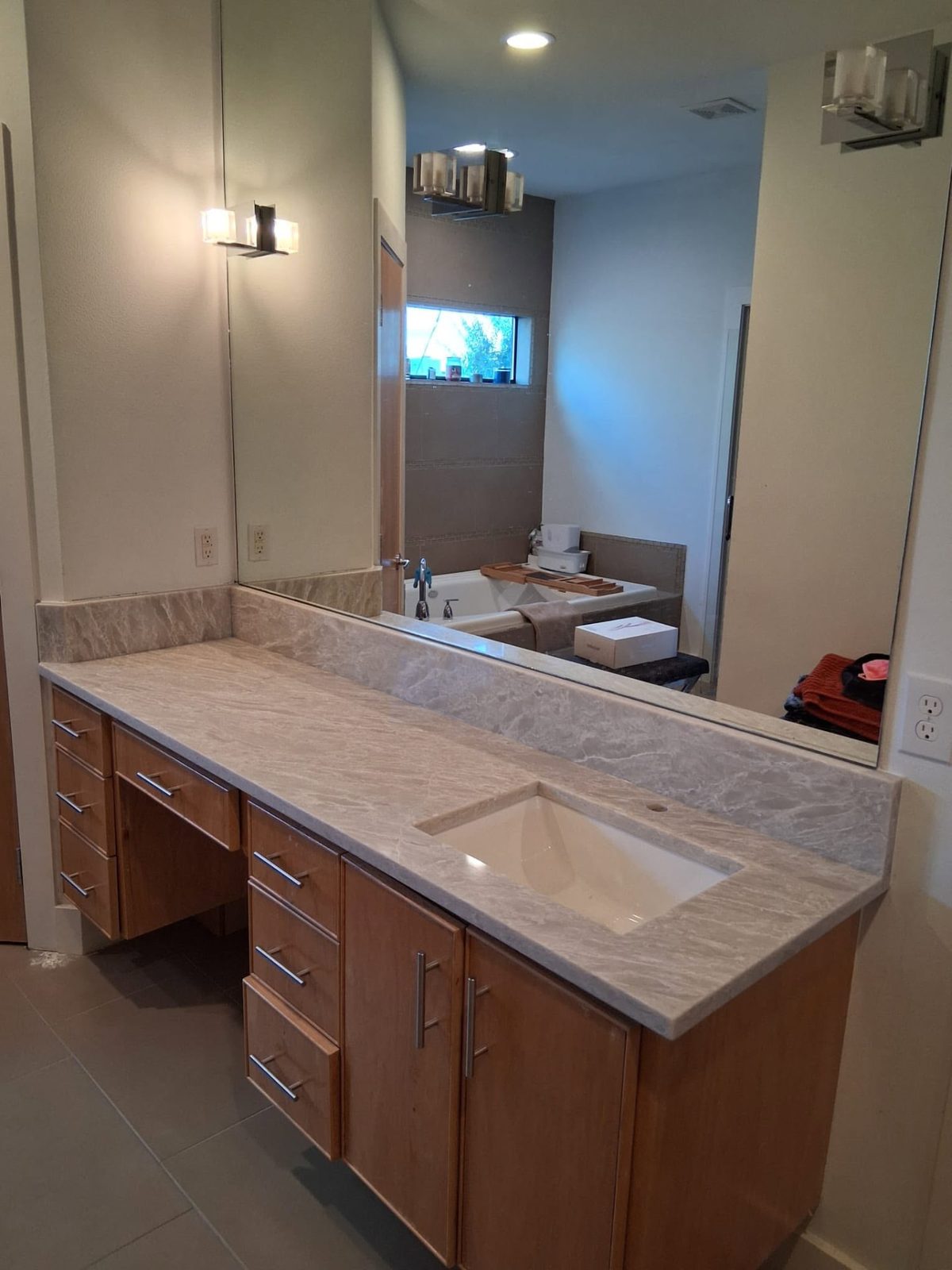 Master bath vanity run in cream marbled stone with a matching backsplash.