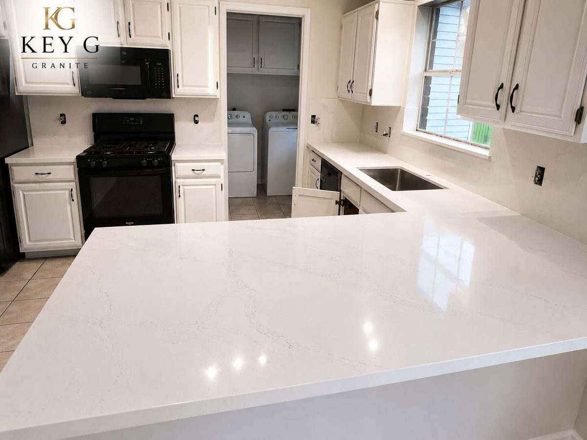 Close view of a white quartz kitchen peninsula with soft grey veining.