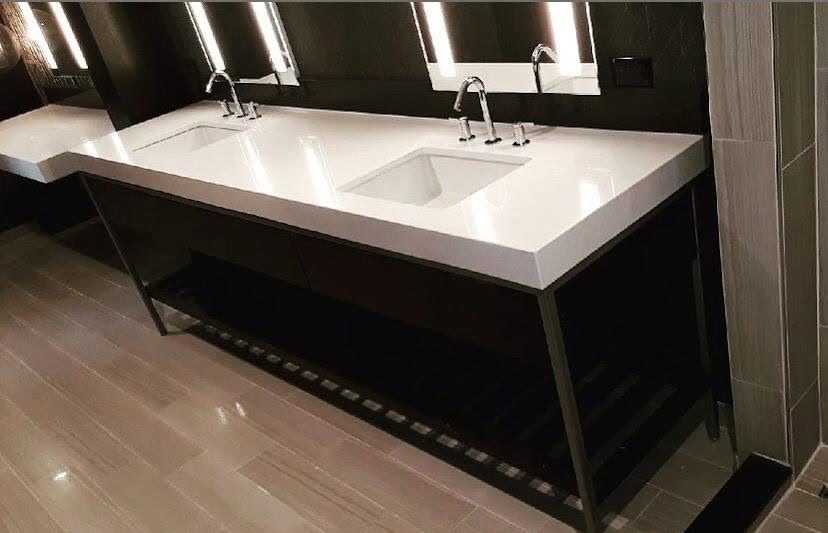 White double vanity top with dark cabinetry and lit mirrors.