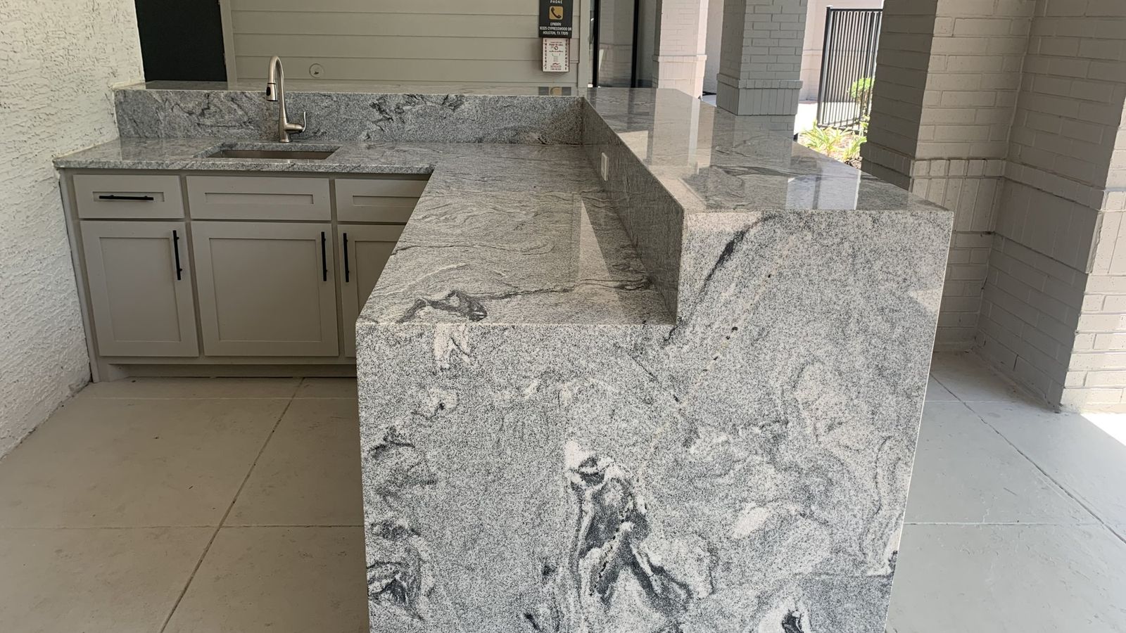 Outdoor kitchen with stone countertops and a waterfall island.