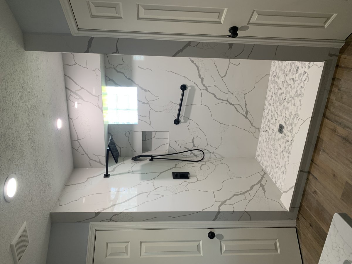 Bathroom with white veined stone shower walls and countertop.